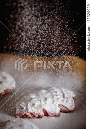 Sprinkle icing sugar over the Christmas cookies 85329009