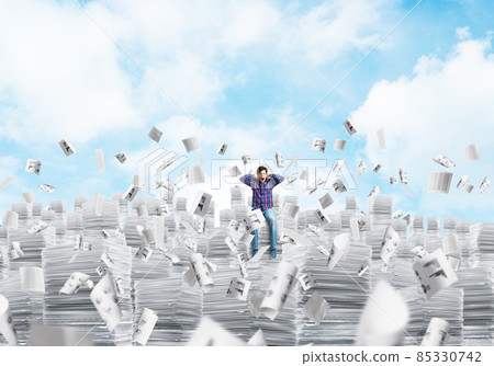 Attractive man sitting on pile of paper documents. 85330742