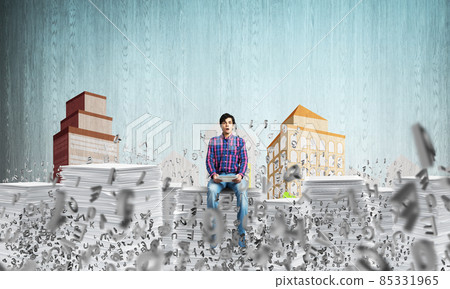 Young man sitting on pile of paper documents. 85331965