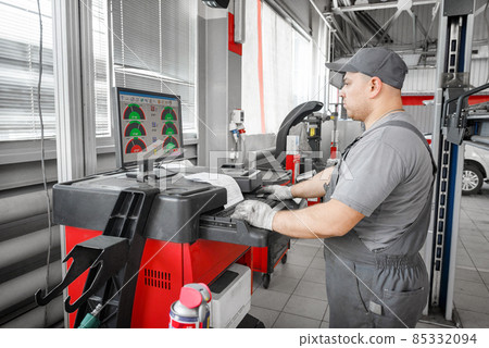 Tire clamped with aligner undergoing auto wheel alignment in garage. Tire clamped with aligner undergoing auto wheel alignment in garage. 85332094