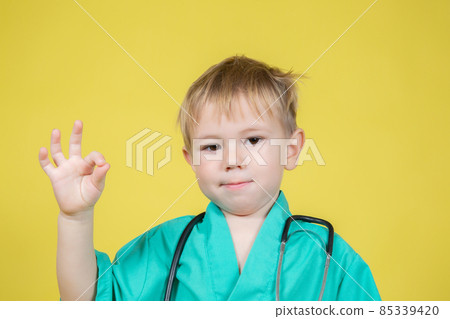 Portrait of little boy dressed in doctors green showing ok gesture 85339420