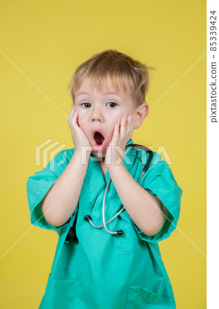 Portrait of shocked little boy dressed in doctors green posing emotionally Portrait of shocked little boy dressed in doctors green posing emotionally 85339424
