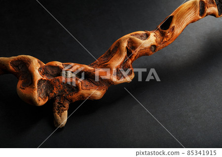 Textured curved Wooden snag of brown color with texture on a black background with free space. 85341915