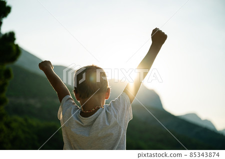 Young child with arms in the air welcoming rising sun 85343874