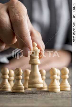 Man playing chess moving the queen piece Man playing chess moving the queen piece 85343878
