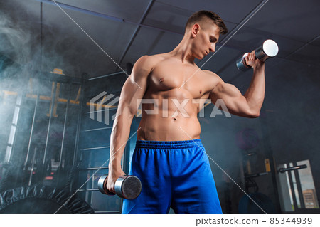 Man doing heavy weight exercise with dumbbells in gym Man doing heavy weight exercise with dumbbells in gym 85344939