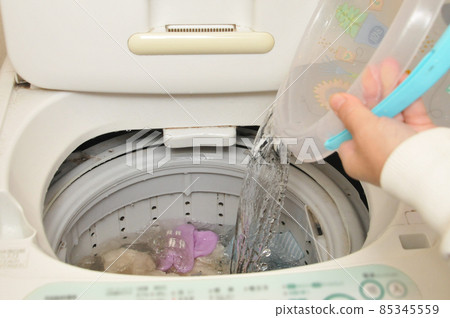 Housewife who transfers the remaining hot water from the bath to the washing machine 85345559