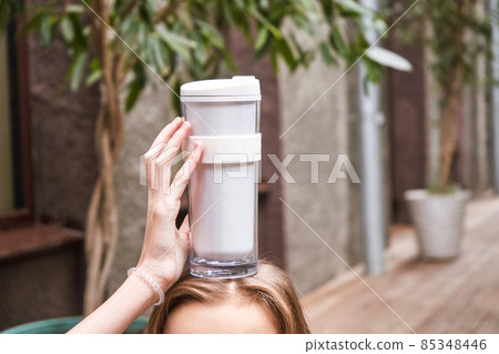 Pretty girl drink beverage outdoors. Buy takeaway coffee in own cup. Real people Pretty girl drink beverage outdoors. Buy takeaway coffee in own cup. Real people 85348446