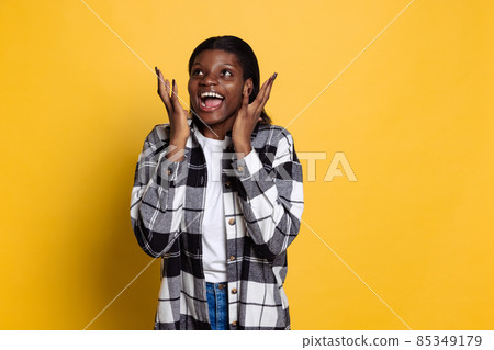 Surprised young beautiful dark skinned girl looking at camera isolated on yellow studio background. Surprised young beautiful dark skinned girl looking at camera isolated on yellow studio background. 85349179