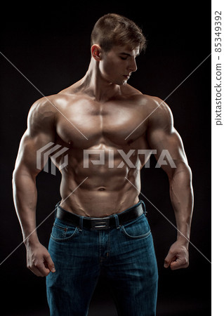 Muscular bodybuilder guy doing posing over black background 85349392