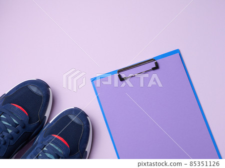 pair of blue textile sneakers on a purple background, top view 85351126