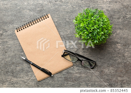 Modern office desk table with notebook and other supplies with green tree. Blank notebook page for you design. Top view, flat lay Modern office desk table with notebook and other supplies with green tree. Blank notebook page for you design. Top view, flat lay 85352445