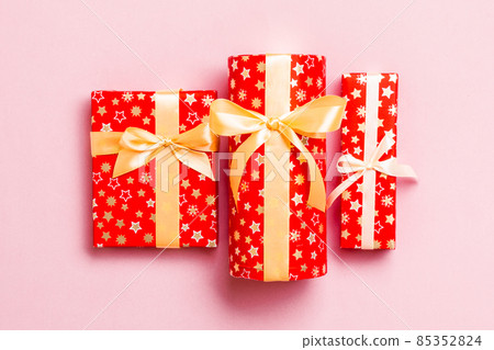Gift box with gold bow for Christmas or New Year day on pink background, top view Gift box with gold bow for Christmas or New Year day on pink background, top view 85352824