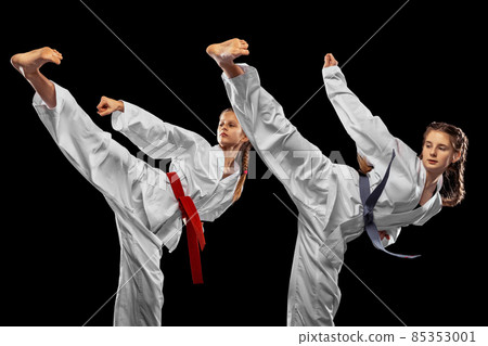 Two young girls, teens, taekwondo athletes training together isolated over dark background. Concept of sport, education, skills 85353001