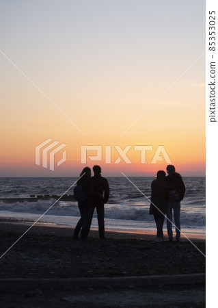 two couples in love embrace at sunset by the sea. two couples in love embrace at sunset by the sea. 85353025