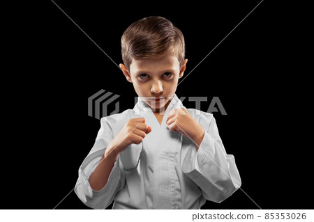 One little kid, boy, taekwondo athlete posing isolated over dark background. Concept of sport, education, skills One little kid, boy, taekwondo athlete posing isolated over dark background. Concept of sport, education, skills 85353026