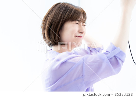 婦女用吹風機烘乾她的頭髮。 85353128