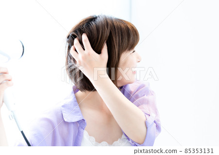 婦女用吹風機烘乾她的頭髮。 85353131