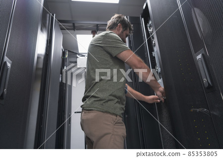 IT engineer working In the server room or data center The technician puts in a rack a new server of corporate business mainframe supercomputer or cryptocurrency mining farm. IT engineer working In the server room or data center The technician puts in a rack a new server of corporate business mainframe supercomputer or cryptocurrency mining farm. 85353805
