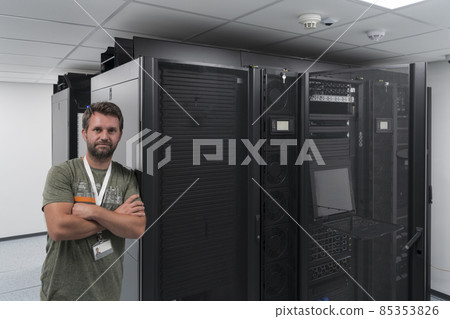 Portrait of male technician or network administrator standing brave as a hero with arms crossed in data center server room. Portrait of male technician or network administrator standing brave as a hero with arms crossed in data center server room. 85353826
