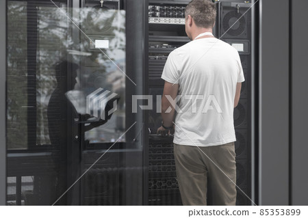 Technicians team updating hardware inspecting system performance in super computer server room or cryptocurrency mining farm. 85353899