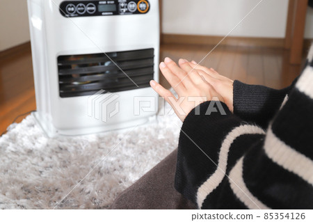 A woman who warms up with a fan heater 85354126