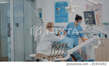 Dentist and nurse examining teeth of patient in dentistry cabinet Dentist and nurse examining teeth of patient in dentistry cabinet 85354262