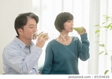 Father and daughter drinking vegetable juice 85354630