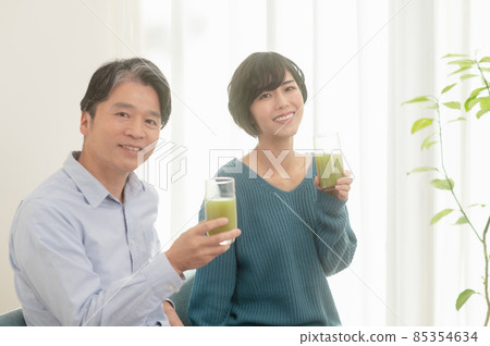 Father and daughter drinking vegetable juice 85354634