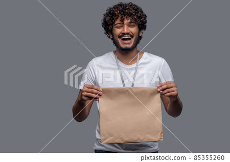 High-spirited deliveryman holding the package with both hands before him 85355260