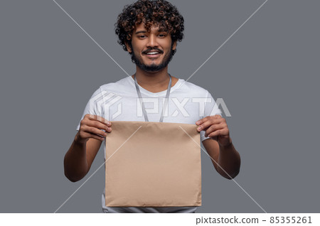 Joyous man with a package posing against the gray background 85355261