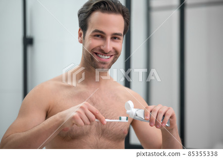 Young handsome man squeezing toothpaste on a toothbrush 85355338