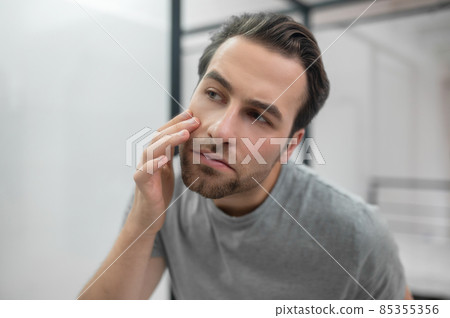 Man near the mirror scrutinizing himself 85355356