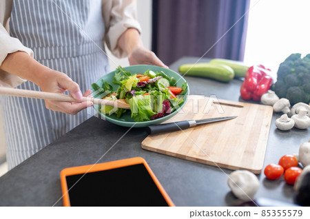 Woman cutting vegetables on a cutting board Woman cutting vegetables on a cutting board 85355579