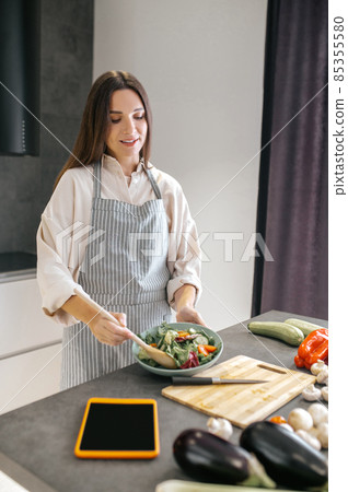 Woman cutting vegetables on a cutting board Woman cutting vegetables on a cutting board 85355580