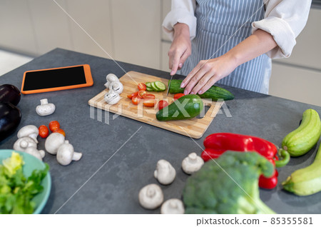 Woman cutting vegetables on a cutting board Woman cutting vegetables on a cutting board 85355581