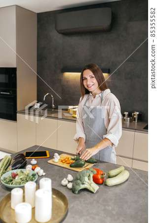 Long-haired young housewife cooking in the kitchen Long-haired young housewife cooking in the kitchen 85355582