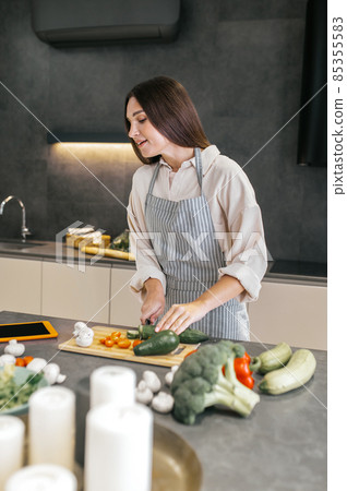 Long-haired young housewife cooking in the kitchen Long-haired young housewife cooking in the kitchen 85355583