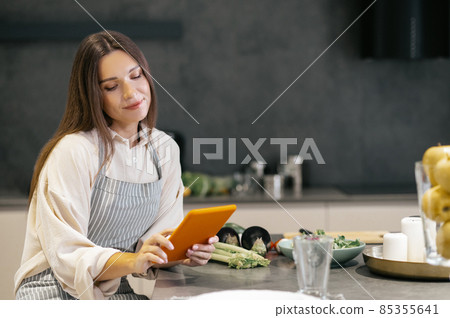 Young woman sitting in the kitchen and looking thoughtful 85355641