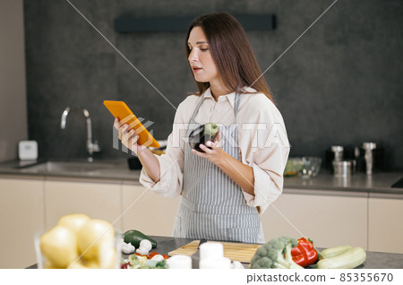 Young housewife looking for new cooking ideas on internet Young housewife looking for new cooking ideas on internet 85355670