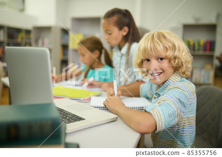 Boy sitting at table looking at camera and girls 85355756