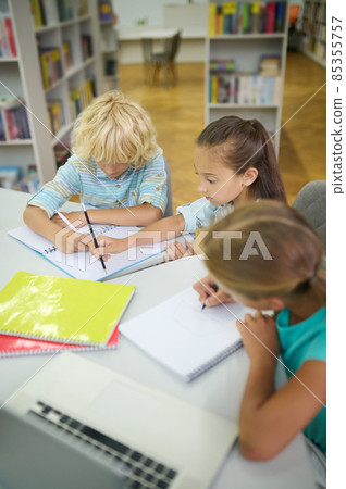 Girls and boy doing lessons in library Girls and boy doing lessons in library 85355757