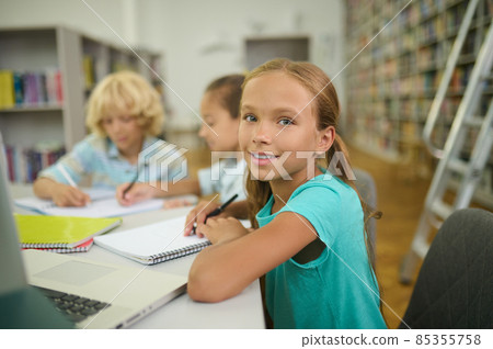 Girl with pencil and copybook looking at camera Girl with pencil and copybook looking at camera 85355758
