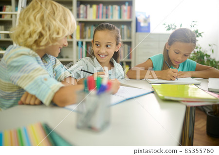 Girl looking at boy writing at table Girl looking at boy writing at table 85355760