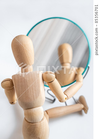 Wooden dummy looks at its reflection in the mirror Wooden dummy looks at its reflection in the mirror 85356701
