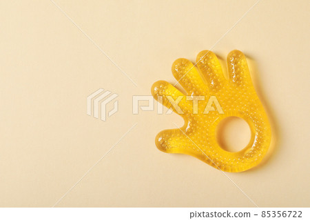 Baby rattle in the shape of a palm on a beige background Baby rattle in the shape of a palm on a beige background 85356722