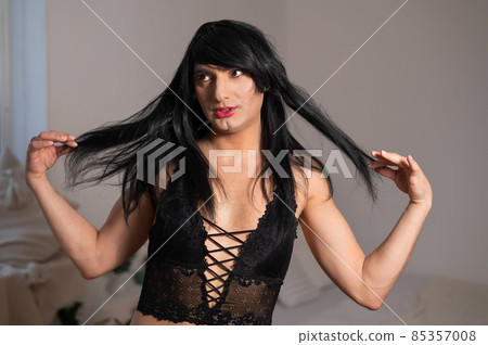 A homosexual guy in black lace underwear and a wig grimaces at the camera. A homosexual guy in black lace underwear and a wig grimaces at the camera. 85357008