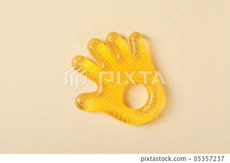 Baby rattle in the shape of a palm on a beige background Baby rattle in the shape of a palm on a beige background 85357237