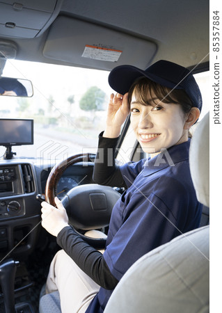 A courier woman turning around in the car 85357884