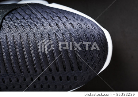 Running shoes with mesh and black and white soles close-up on a dark background. Running shoes with mesh and black and white soles close-up on a dark background. 85358259
